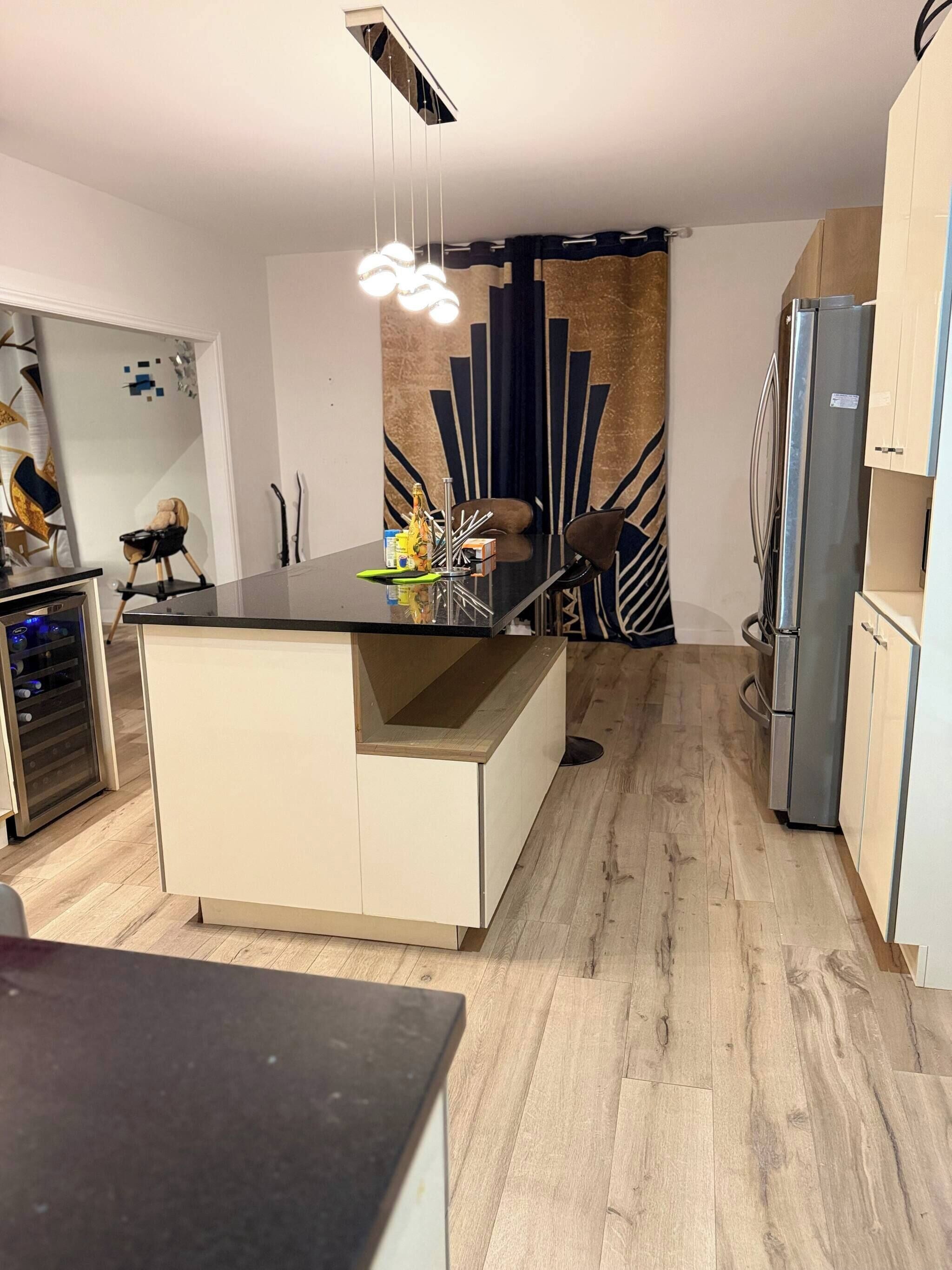 A modern kitchen with a central island, a built-in wine cooler, and a refrigerator.