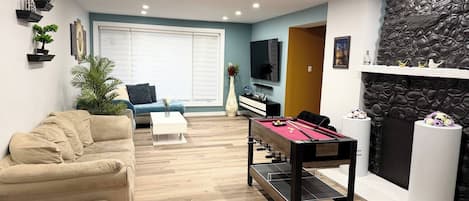 Una sala de estar con sofá, mesa de centro, mesa de billar y chimenea.