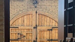 En pardörr av trä med ett metallhandtag och ett lås, placerad mot en mur av tegelsten.