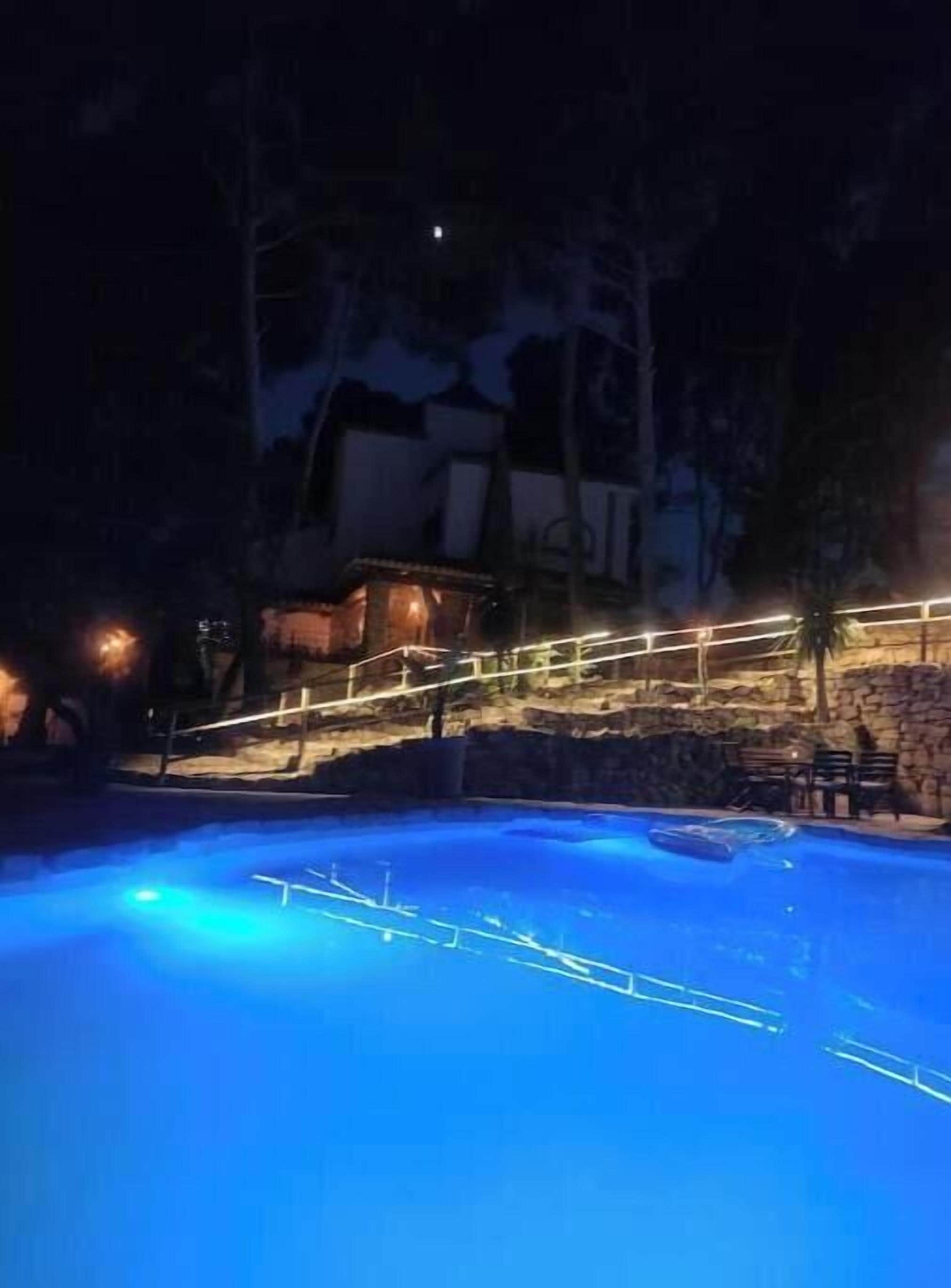 Une piscine avec un mur en pierre et une terrasse en bois.