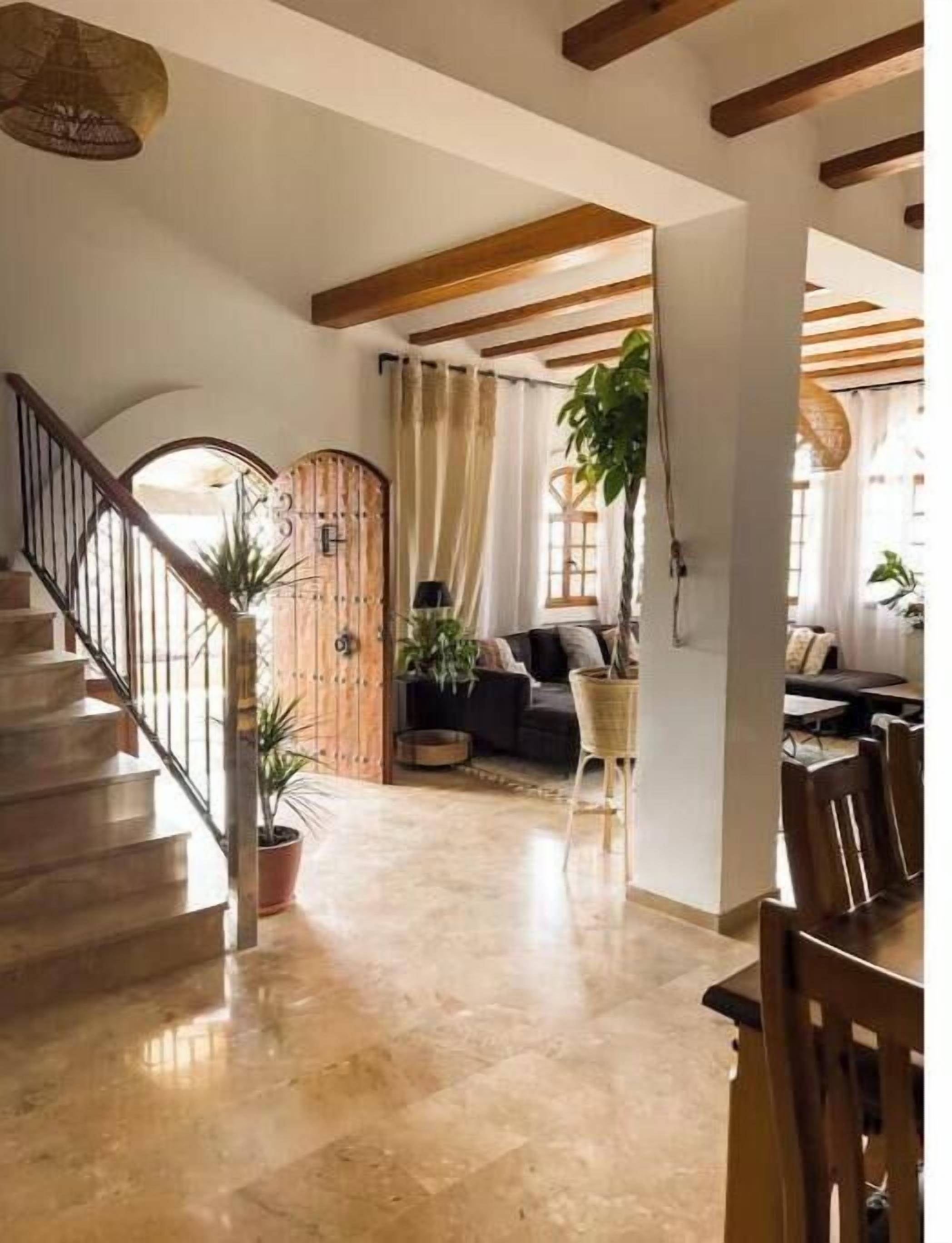 Un vaste espace de vie comprenant un escalier, des poutres en bois, un canapé et une table à manger.