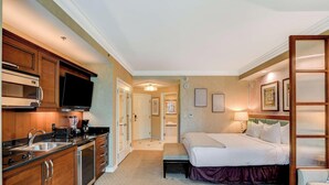 A hotel room with a kitchenette, a bed, a bedside table, and a bathroom visible through an open door. - MGM Signature-04-609 Strip View Jacuzzi Studio (Las Vegas)