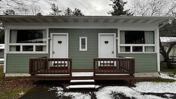 A small, two-room cabin with a front porch and steps leading to the entrance.