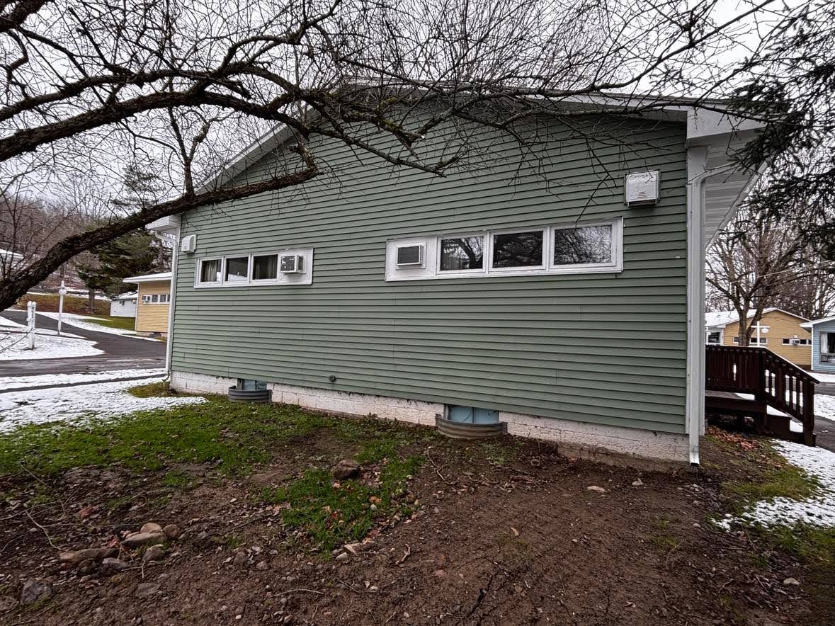 Una casa de un piso con fachada verde, un pequeño porche y un ventanal visible.
