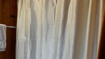 A bathroom with a white toilet, a shower curtain, and a wooden door.