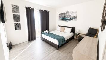 A hotel room with a bed, a desk, a chair, and artwork on the walls.