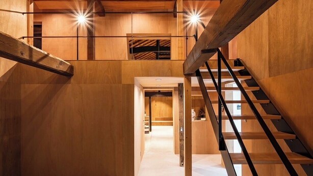 Interior de madera con una escalera, vigas de madera y lámparas colgantes.