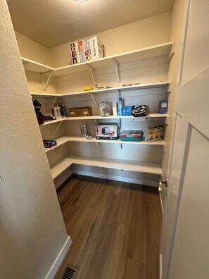 A compact kitchen with white shelves, a microwave, and various kitchen items.