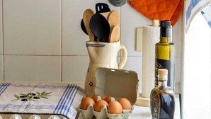 Eine Küchenarbeitsplatte mit Herd, Eiern, einer Olivenölflasche und Küchenutensilien.