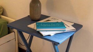 Ein kleiner Tisch mit Lampe und Büchern, ein Stuhl und ein Teppich.
