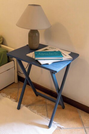 Ein kleiner Tisch mit Lampe und Büchern, ein Stuhl und ein Teppich.