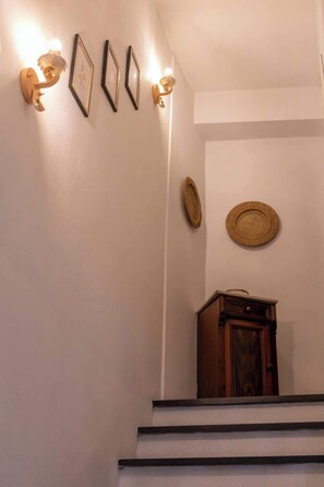 Eine Treppe mit einem Holzkabinett am Fuß, einer Wand mit gerahmten Bildern und zwei Wandleuchten.