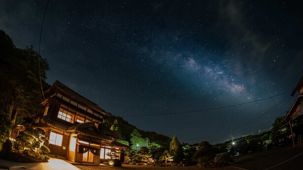 A traditional Japanese building with a wooden exterior, a tiled roof, and a well-lit entrance. - Kominka No Yado Wagoromo (Otaki)