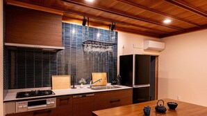 A kitchen with wooden cabinets, a stove, a sink, and a refrigerator. - Kominka No Yado Wagoromo (Otaki)