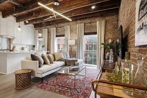 A modern living room with a sofa, coffee table, and a red patterned rug. - Luxe 8BR CBD Duplex, Private Courtyard (New Orleans)