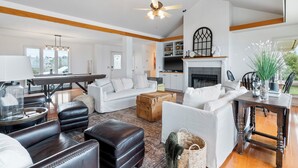 A spacious living room with a fireplace, a dining area, and a kitchen in the background. - Bluff View House has vast open water views of Greers Ferry Lake in Arkansas (Quitman)