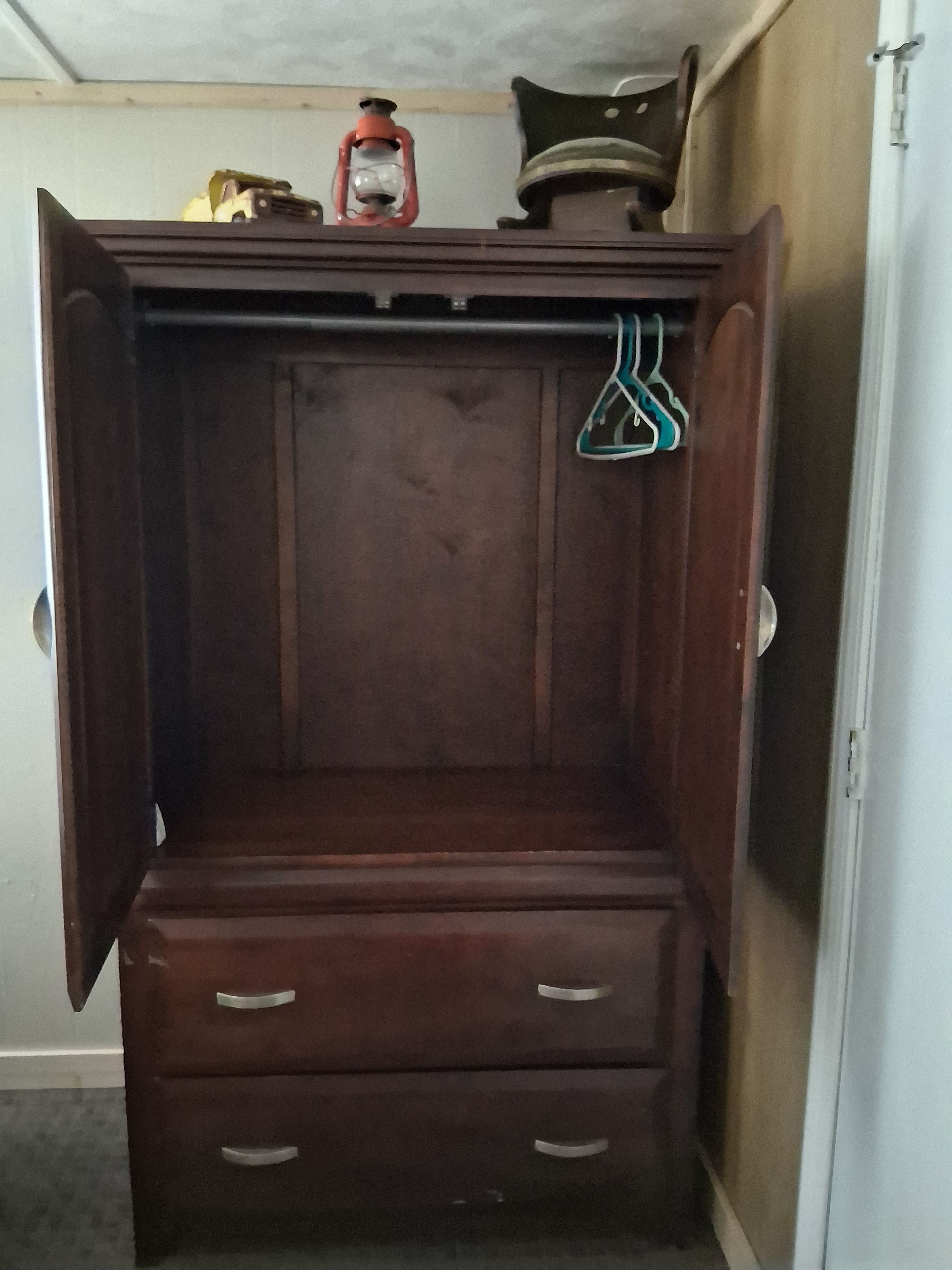 Ein Holzschrank mit zwei Schubladen und einer Kleiderstange.