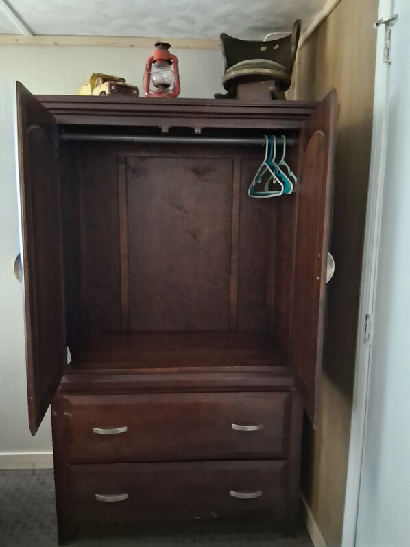 A wooden wardrobe with two drawers and a hanging space.