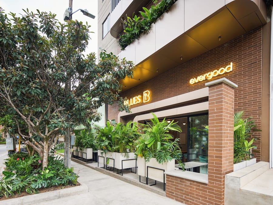 Un edificio con un letrero que dice 'evergood' y una fila de mesas al aire libre.