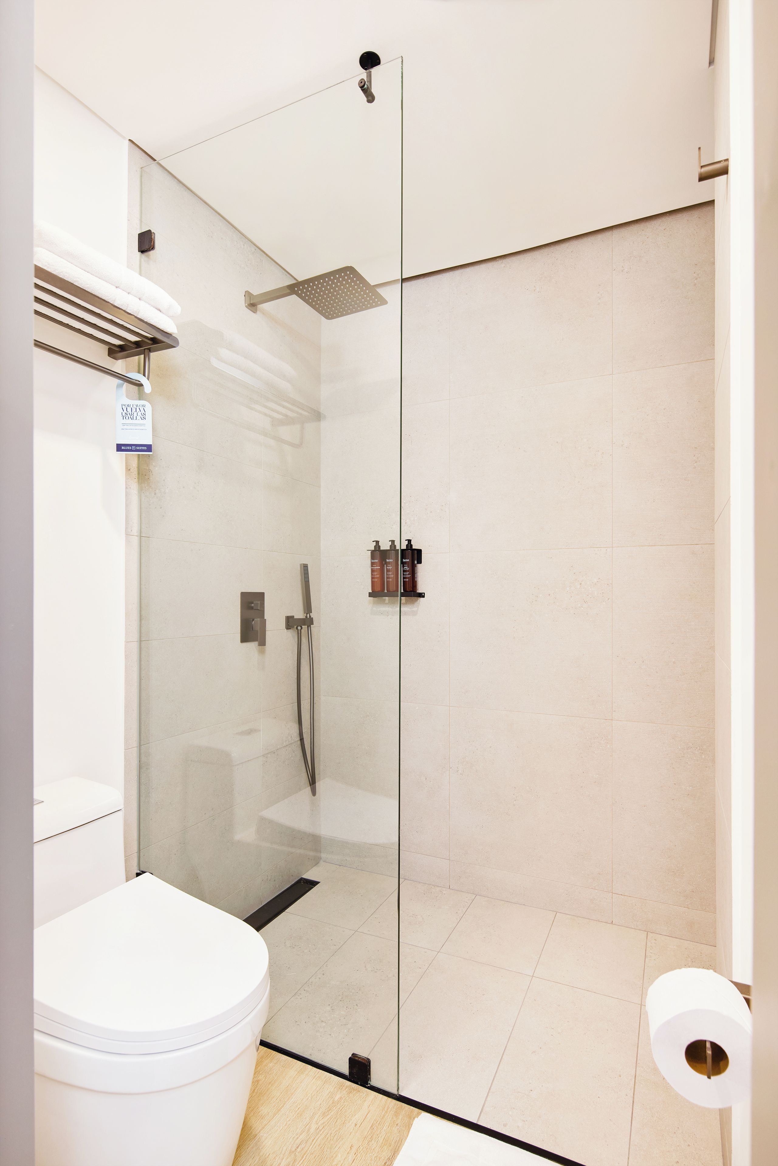 Une salle de bain moderne avec une douche à parois de verre, des toilettes et un rouleau de papier toilette visible.
