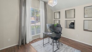 Un espace de bureau moderne comprenant un bureau, une chaise, un ordinateur et une grande fenêtre avec des rideaux.