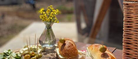 A wooden board with food items, a wicker basket, and a checkered tablecloth.