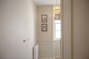 En hall med ett element, en hängande lampa och två inramade tavlor på väggen.