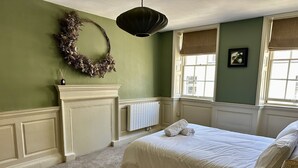 Un dormitorio con cama, un radiador, una ventana con vistas y una guirnalda en la pared.