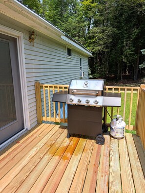 A barbecue grill on a wooden deck with a house in the background. - Lakeside Haven on Whites Pond (Palmyra)