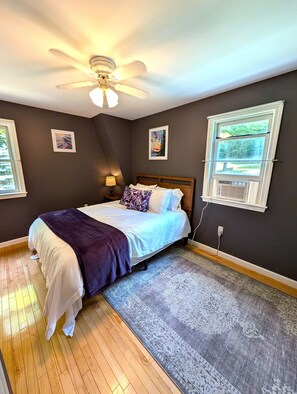 A bedroom with a bed, a ceiling fan, a window, and a rug. - Lakeside Haven on Whites Pond (Palmyra)