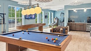 Een pooltafel met ballen, een bank en een keuken met kasten en een koelkast.