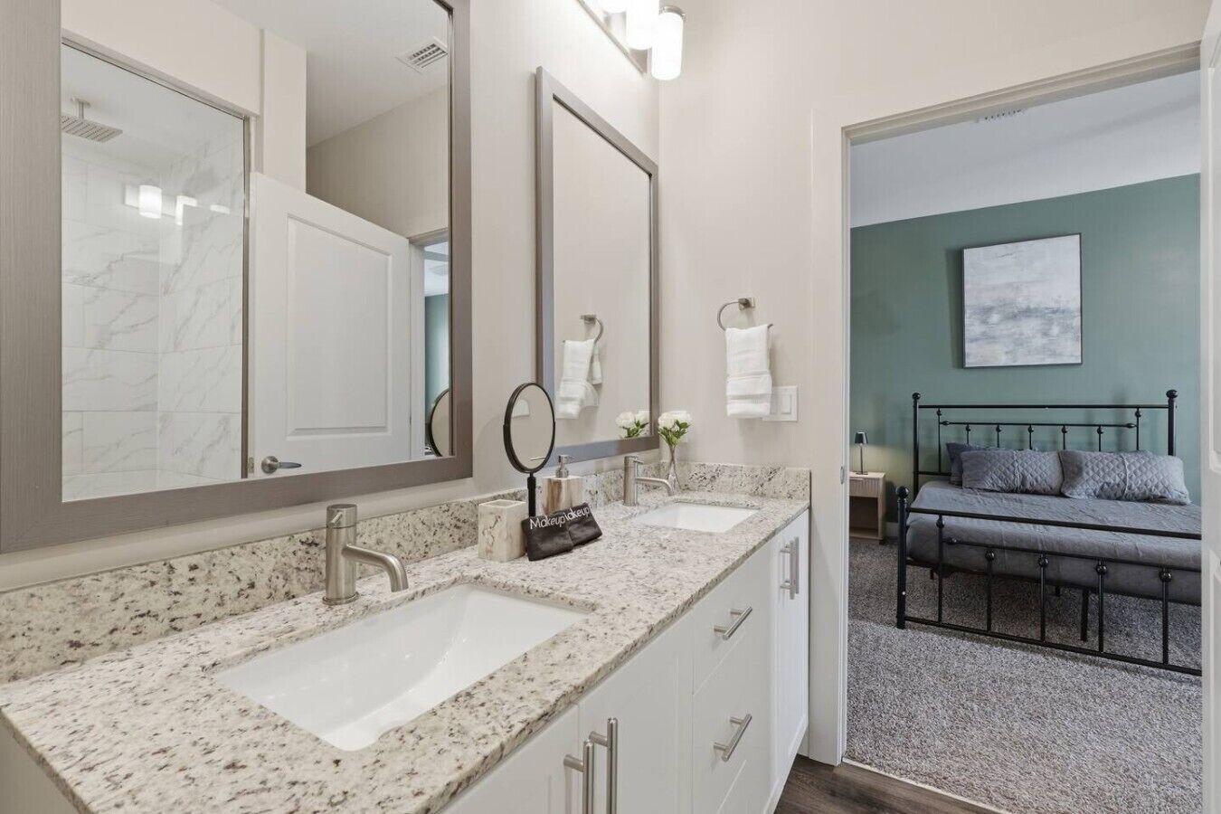A bathroom with two sinks, a large mirror, and a vanity with drawers.