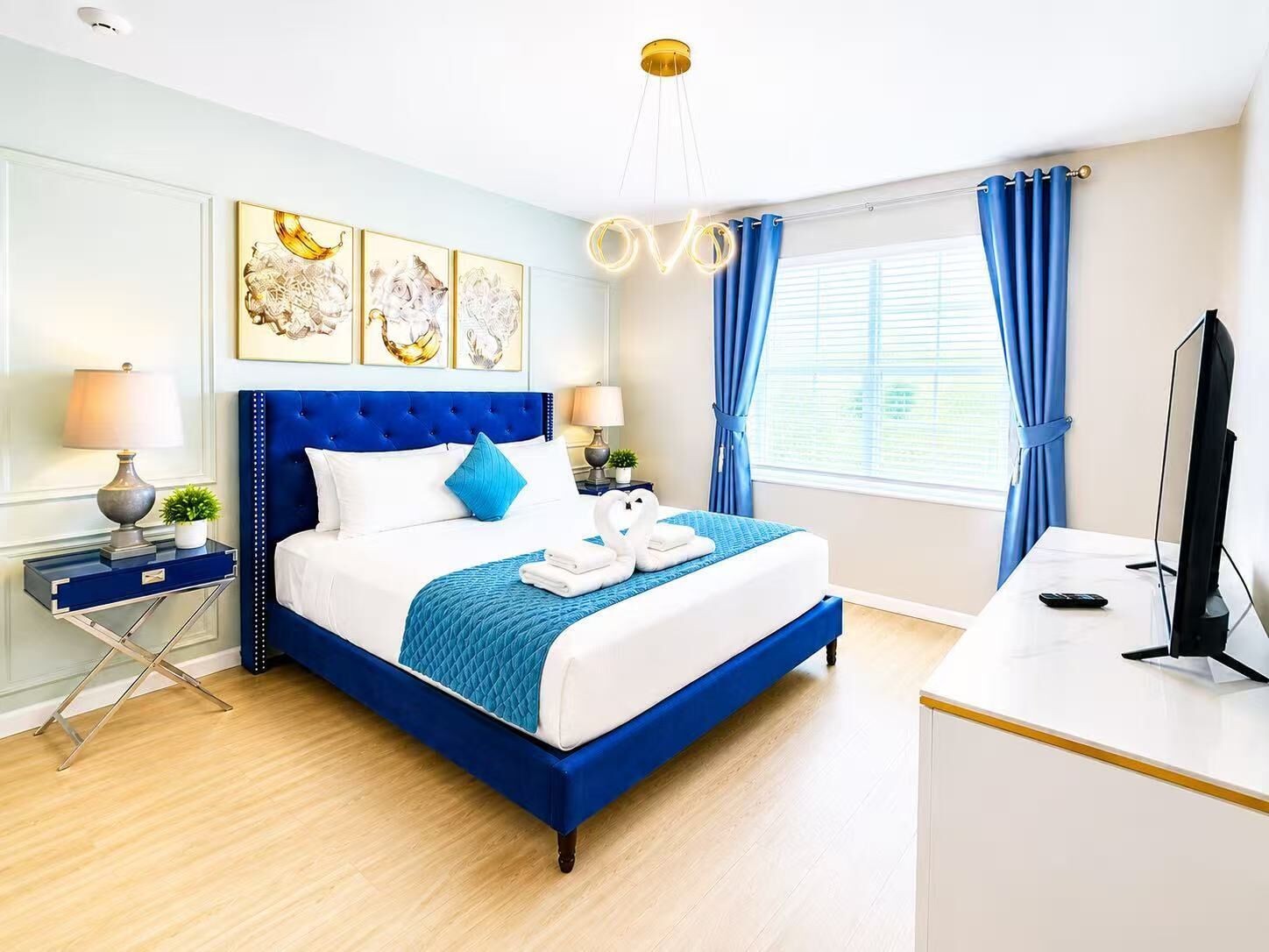 Ein Hotelzimmer mit einem großen Bett, einem Schreibtisch, einem Fernseher und Bildern an der Wand.