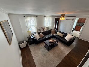 A living room with a sectional sofa, a coffee table, and a ceiling fan. - Fishtown home (Philadelphia)