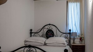 Ett sovrum med en säng, ett nattduksbord, en lampa och ett fönster med gardiner.