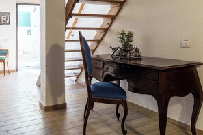 Ein Zimmer mit einem Holztisch, einem Stuhl, einer Pflanze und einer Treppe.