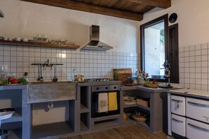 Eine Küche mit Gasherd, Backofen und Fenster.