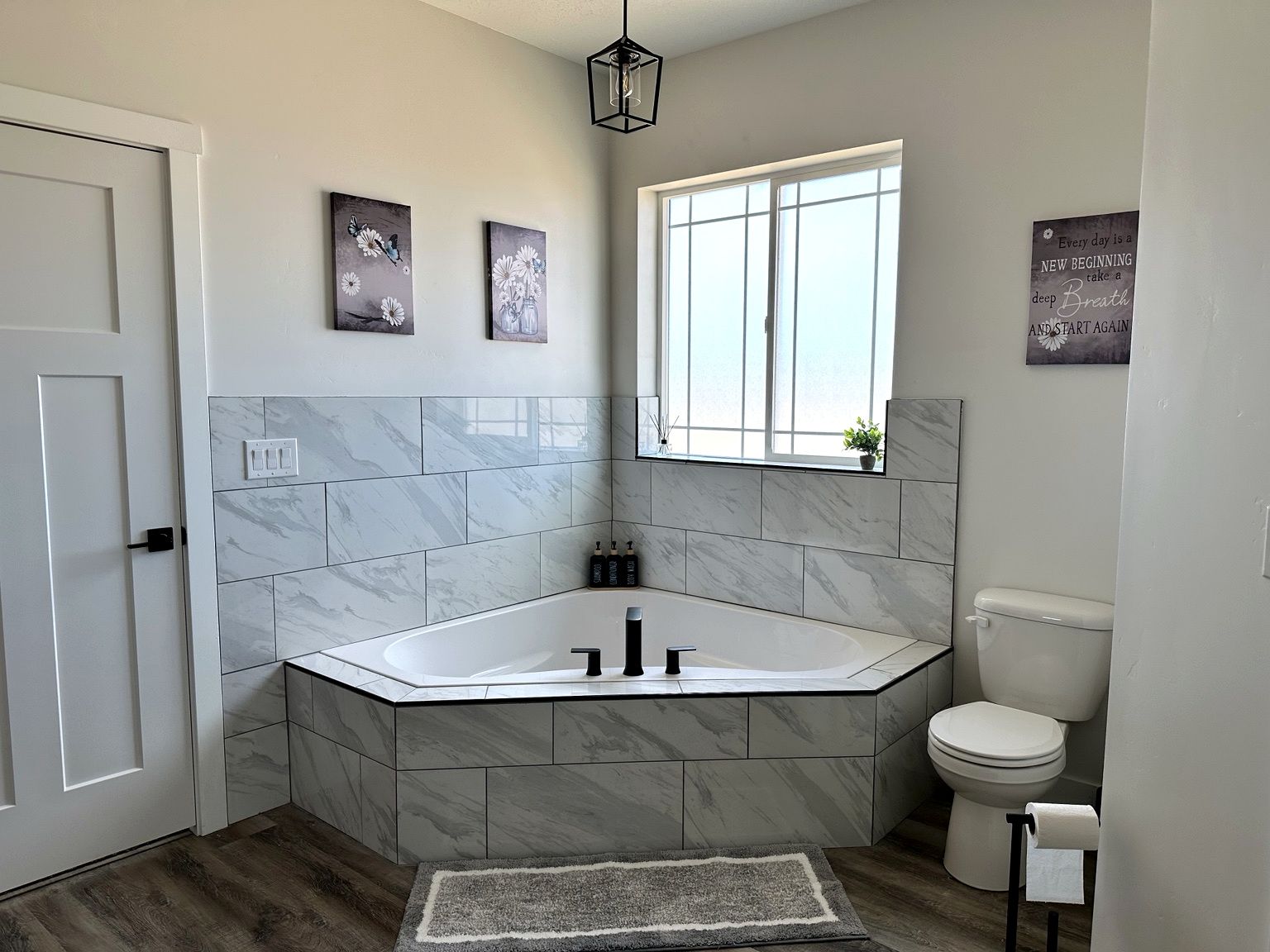 A modern bathroom with a freestanding bathtub, a toilet, and a window providing natural light.