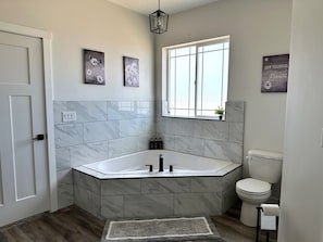 A modern bathroom with a freestanding bathtub, a toilet, and a window providing natural light.