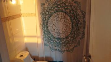 Een badkamer met toilet, wastafel en een douchegordijn met een mandala ontwerp.