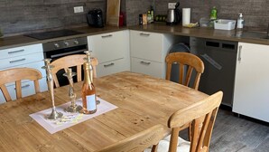 A kitchen with a wooden table, chairs, a stove, and a dishwasher. - An Eifel idyll at the Nürburgring: A spacious oasis of comfort with plenty of room (Herresbach)