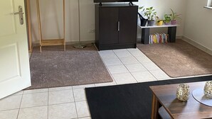 A room with a flat-screen TV, a wooden wardrobe, a small table, and a bookshelf with books. - An Eifel idyll at the Nürburgring: A spacious oasis of comfort with plenty of room (Herresbach)