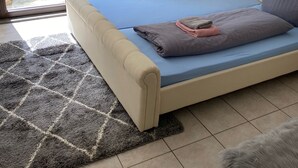 A bedroom with a bed, a small bedside table, a lamp, a wall decoration, and a view of the outside. - An Eifel idyll at the Nürburgring: A spacious oasis of comfort with plenty of room (Herresbach)