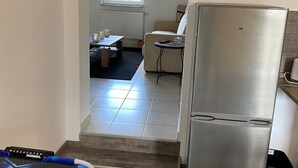 A kitchen with a stainless steel refrigerator, a dining area with a table and chairs, and a window with a view of greenery. - An Eifel idyll at the Nürburgring: A spacious oasis of comfort with plenty of room (Herresbach)
