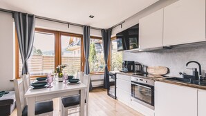Une cuisine moderne avec un coin repas, de grandes fenêtres et une vue sur l’extérieur.