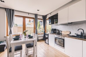 Eine moderne Küche mit Essbereich, großen Fenstern und Blick ins Freie.
