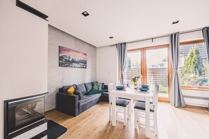 Eine moderne Küche mit Einbauofen, Essbereich mit Tisch und Stühlen sowie ein großes Fenster mit Vorhängen.