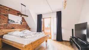 Une chambre avec un lit en bois, une télévision et un mur en briques.