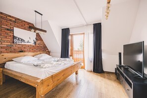Ein Schlafzimmer mit einem hölzernen Bett, einem Fernseher und einer Ziegelwand.