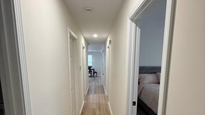 Un couloir doté d’un plancher en bois, de murs blancs et de portes donnant accès aux pièces.